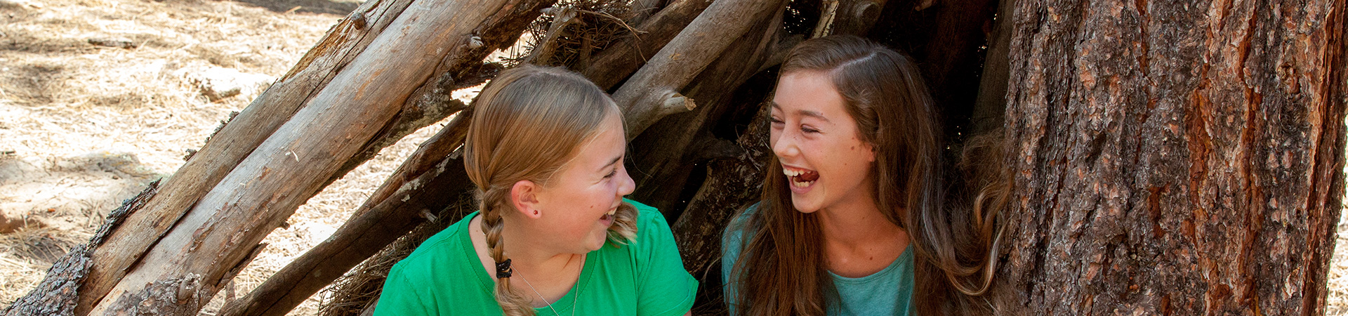  two girl scouts laughing while sitting outdoors 