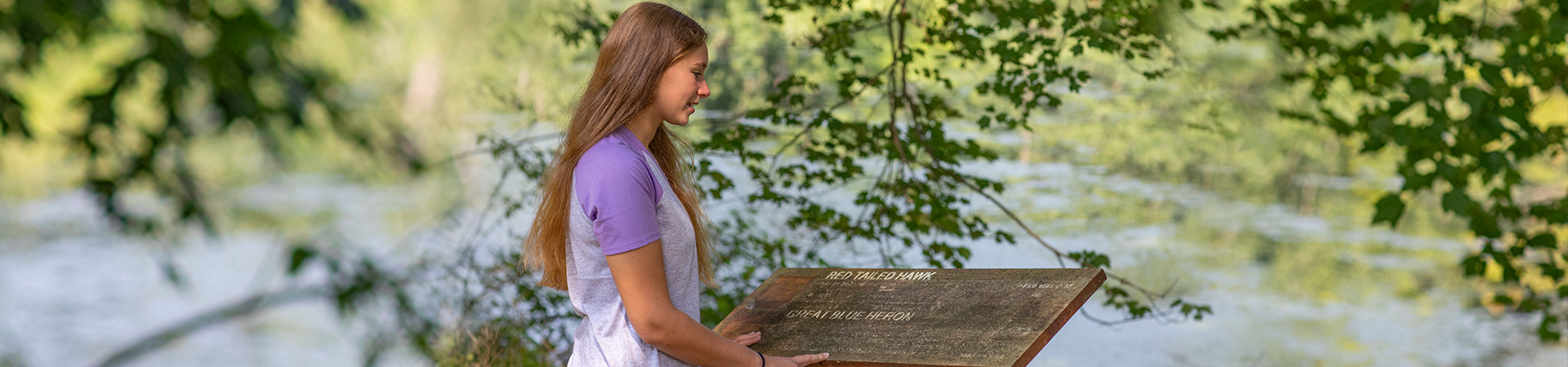  teenage girl scout reading a trail sign at a camp 