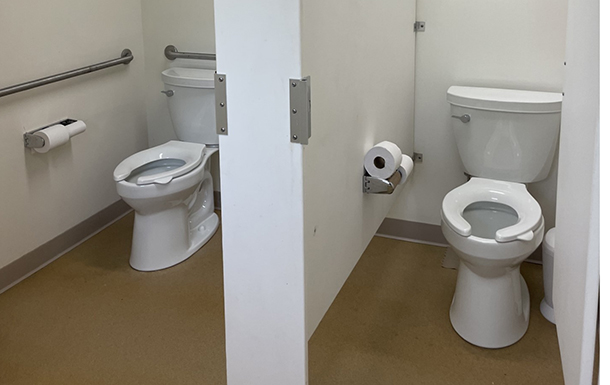 two toilet and bathroom stalls in the gemini building at camp