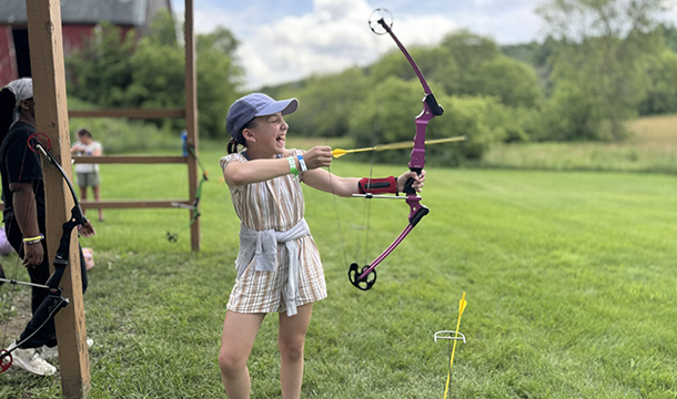 girl laughing while practicing archery