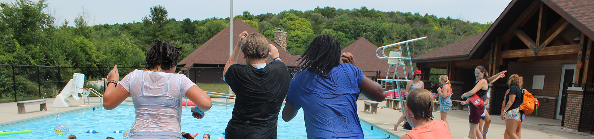  group of girl scouts jumping into a pool at camp while others watch 