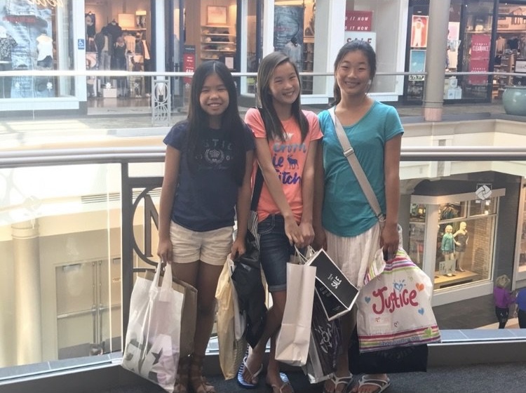 Three girls in a mall holding shopping bags