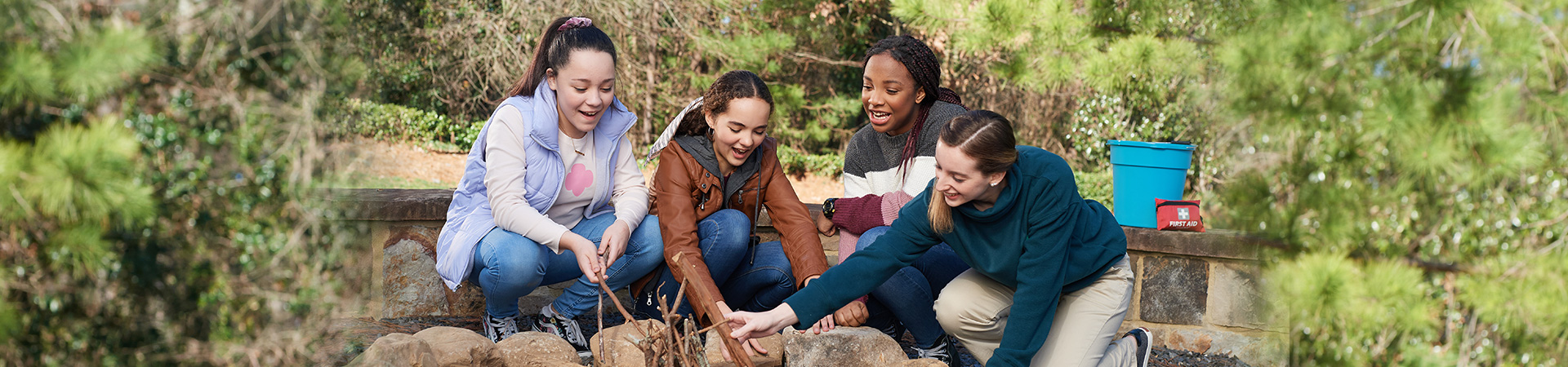  group of teenage girl scouts build a campfire 