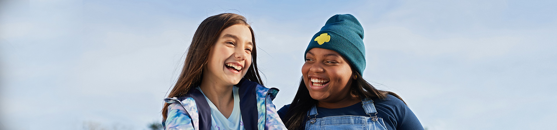  two girl scouts sitting outside laughing 